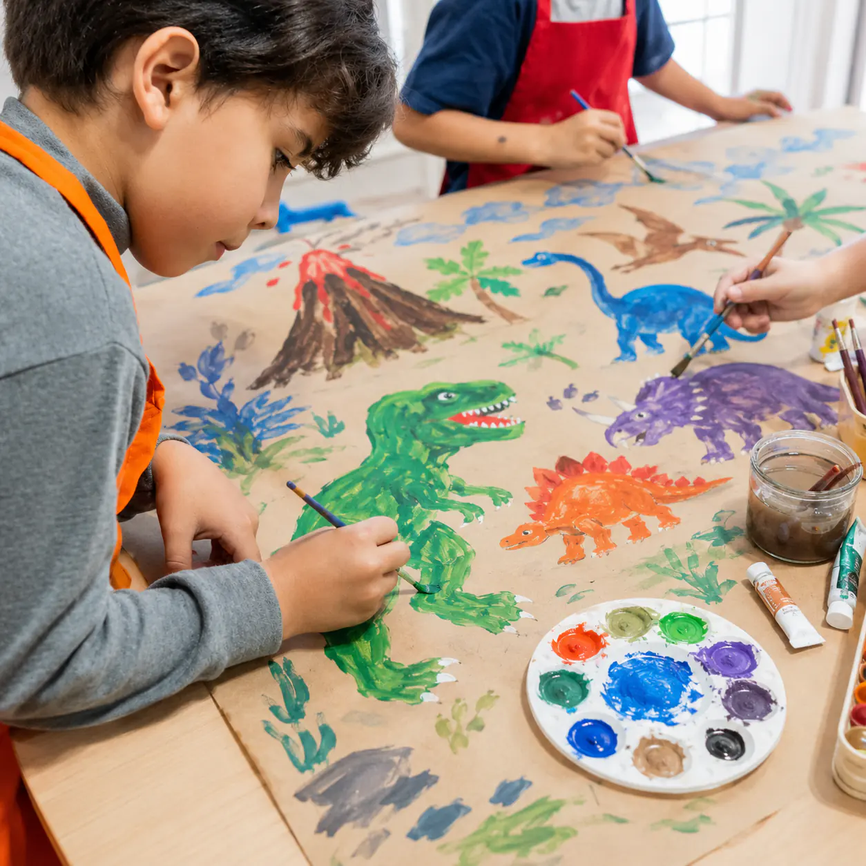 A child painting a dinosaur scene in bright poster paint