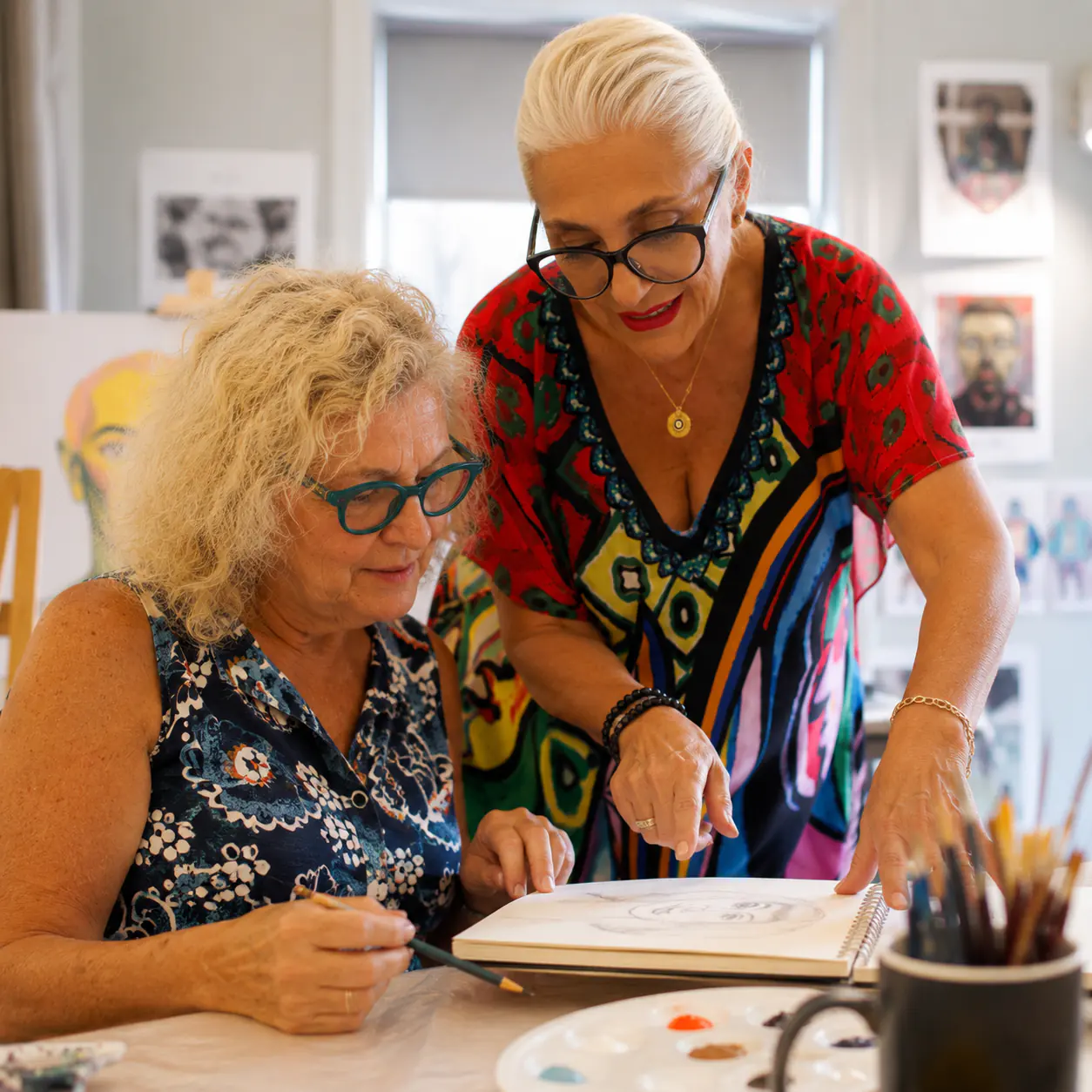 Helen Pestana guiding an adult student through a drawing at the studio table